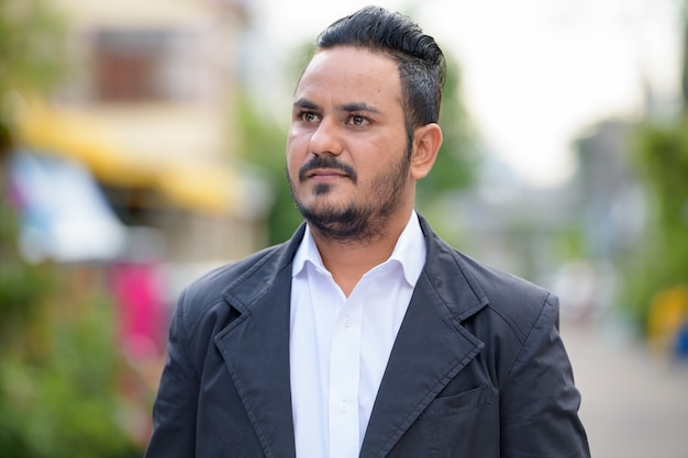 Portrait of bearded Indian businessman wearing suit in the street outdoors