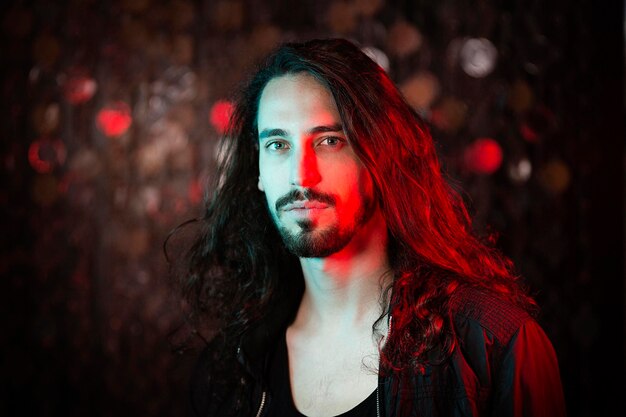 Portrait of bearded long-haired young man in red light