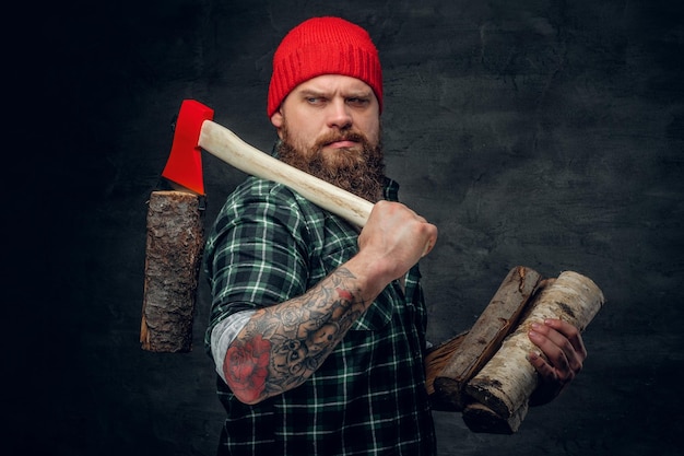 Portrait of bearded lumberjack dressed in a green shirt holds the red axe.