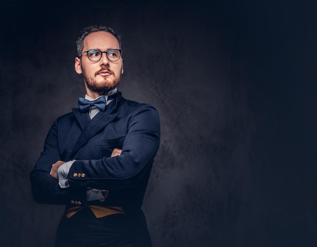 Portrait of a bearded male in glasses and antique suit on a dark