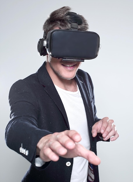 Portrait of bearded male in a suit with virtual reality glasses on his head isolated on grey background