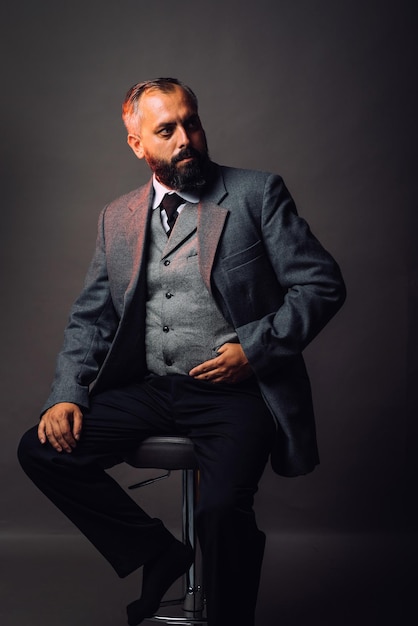 Portrait of bearded man dressed in strict suit looking forward on black background