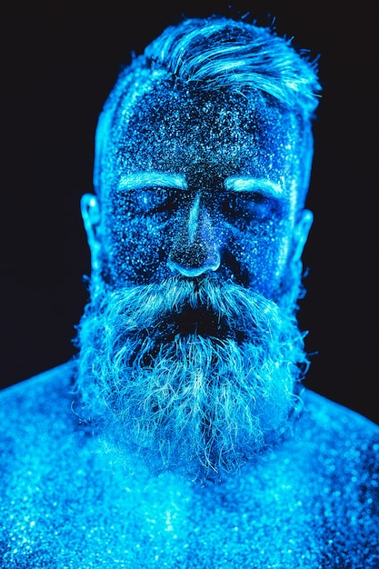 Portrait of a bearded man. Man is painted in ultraviolet powder.