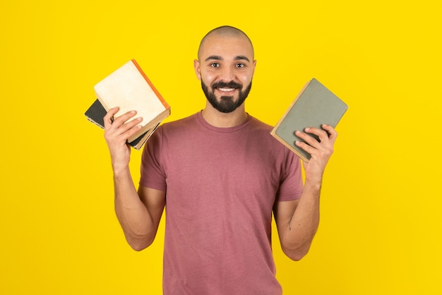 Portrait of a bearded man showing book cover over yellow wall.