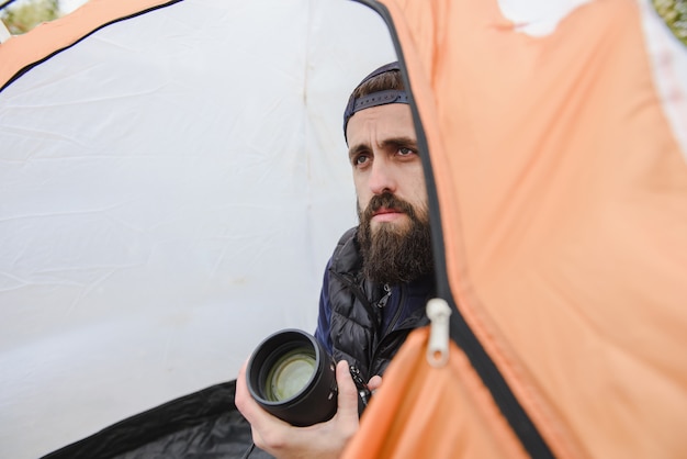 Foto ritratto di un uomo barbuto con una macchina fotografica