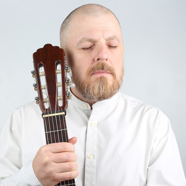 Ritratto di un uomo barbuto con una chitarra classica in mano