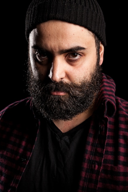 Portrait of bearded man with a hat on black background