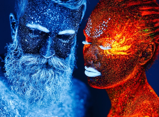 Portrait of a bearded man and woman painted in ultraviolet powder.