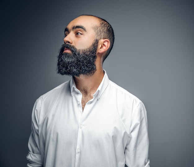 Portrait of bearded mix race male in a white shirt isolated on grey background.