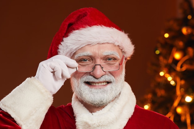 Portrait of bearded Santa Claus in eyeglasses and in Santa hat smiling 