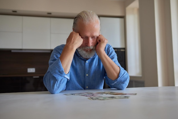 Foto ritratto di un pensionato anziano barbuto con le mani rugose che conta le banconote di rublo russo