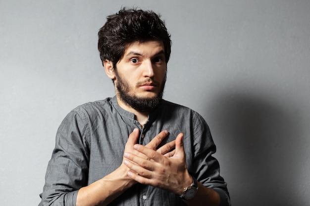 Portrait of bearded young stricken guy with disheveled hair isolated on grey.