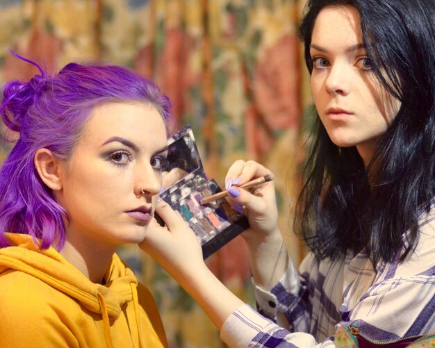 Portrait of beautician applying make-up on woman