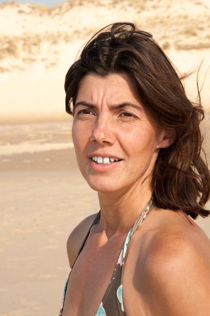 Portrait of beautiful 40yearold brunette woman on beach sand sea coast summer day