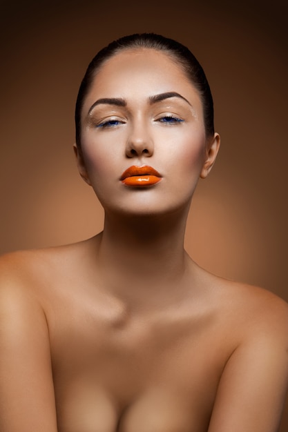 Photo portrait of beautiful adult caucasian woman with make up on brown wall