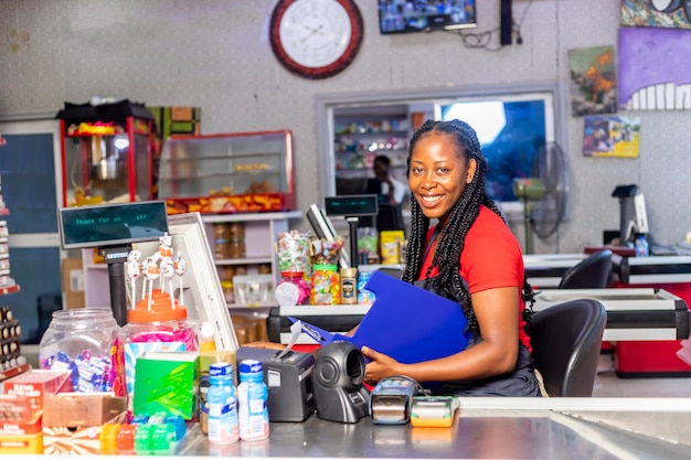 カメラを見て食料品店で働く美しいアフリカ系アメリカ人の笑顔のレジ係の女性の肖像画