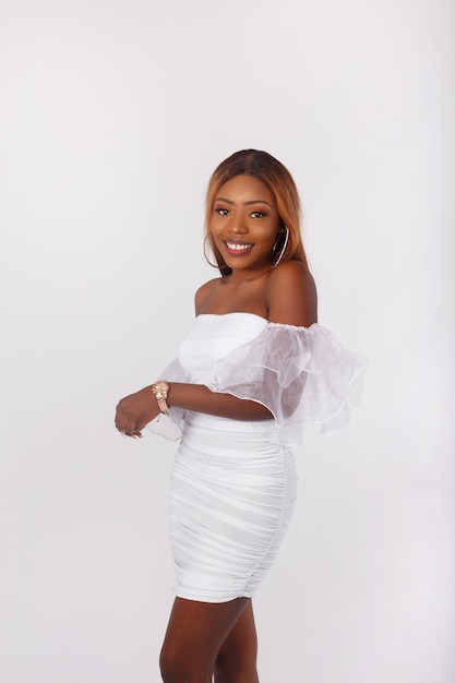 Portrait of a beautiful african american woman in short white dress smiling on white background