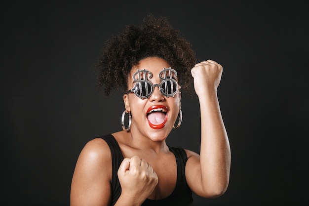 Portrait of a beautiful afro american woman wearing sunglasses standing isolated over black space