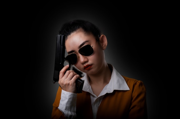 Portrait beautiful Asia woman wearing a yellow suit one hand holding a pistol gun