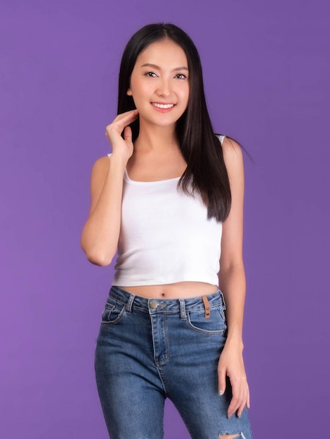 Portrait of Beautiful Asian brunette woman cute girl in white tank top girl standing smile and happiness isolated on purple background