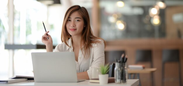 Portrait of beautiful asian business woman working on her project with laptop computer and smiling to the camera