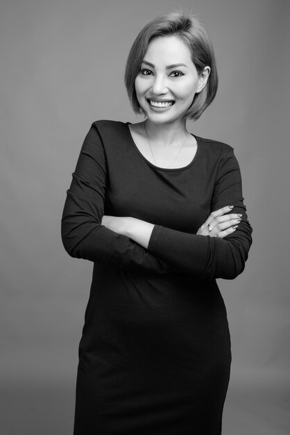 Portrait of beautiful Asian businesswoman on gray in black and white