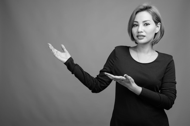 Portrait of beautiful Asian businesswoman on gray in black and white