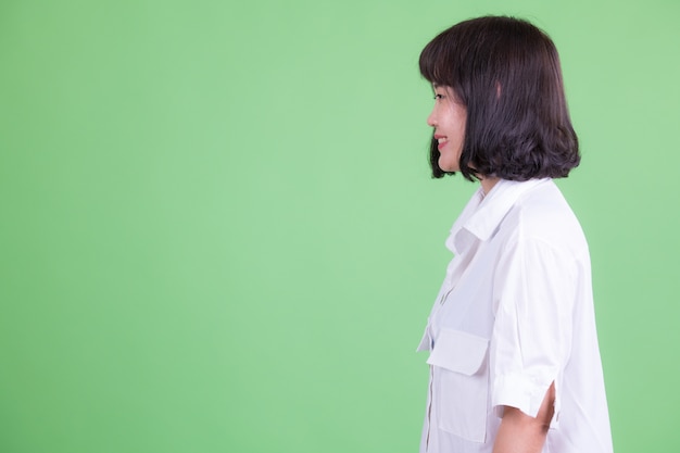 Портрет красивой азиатской бизнес-леди с короткими волосами на фоне цветного ключа или зеленой стены