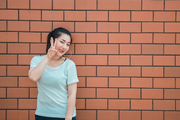 Portrait of beautiful asian chic girl pose for take a picture on brick wallLifestyle of teen thailand peopleModern woman happy concept