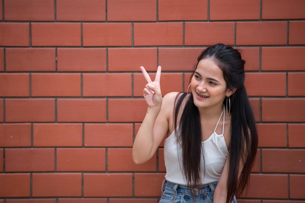 Портрет красивой азиатской шикарной девушки позирует для снимка на фоне стеныОбраз жизни подростков из ТаиландаСовременная женщина счастлива концепцияСтиль панк-рок