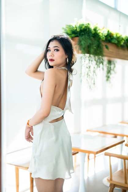 Portrait beautiful asian freelance Success people business woman fashion model in summer white sleeveless dress and coffee in cup in coffee shop