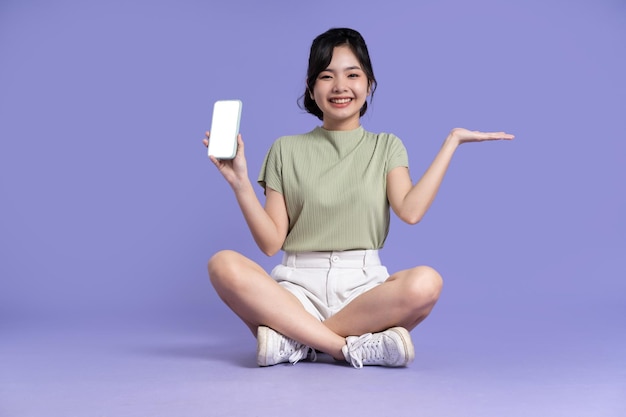 Portrait of beautiful asian girl sitting on purple background