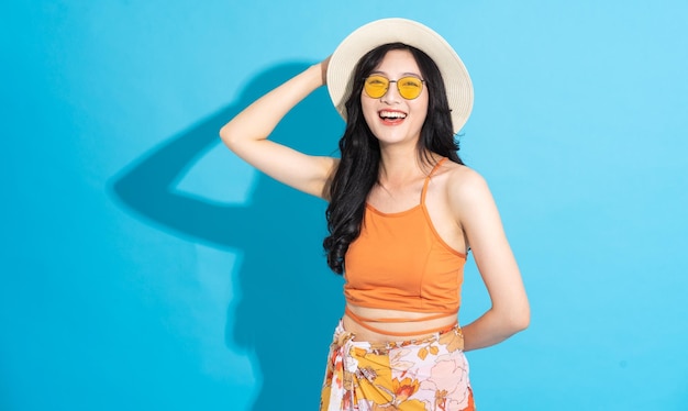 Portrait of a beautiful asian girl in a swimsuit smiling happily on a blue background