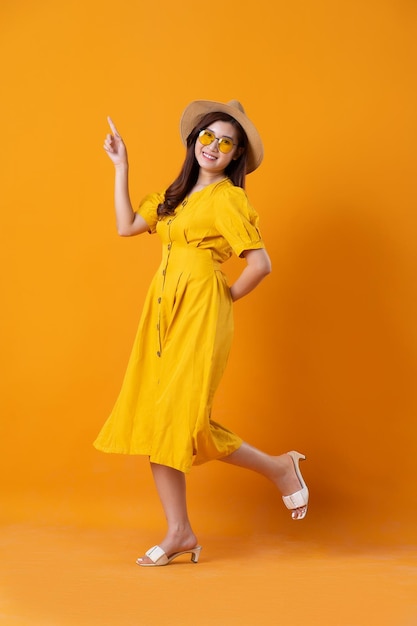 Portrait of beautiful asian girl wearing yellow dress on orange background