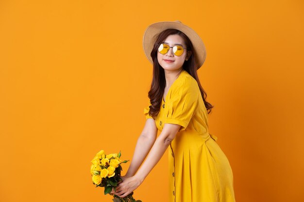 Portrait of beautiful asian girl wearing yellow dress on orange background