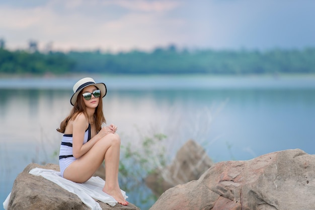 Portrait of beautiful asian sexy woman wear bikini on the rock side sea in the eveningLifestyle of modern womenThailand people