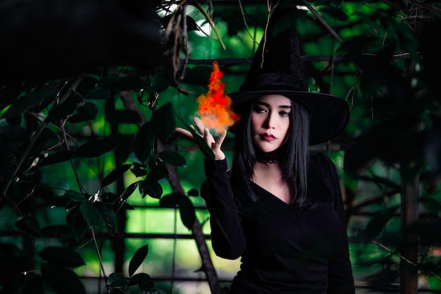 美しいアジアのセクシーな女性の肖像画は、ほうきで黒魔女の衣装を着ていますハロウィーンフェスティバルのコンセプト