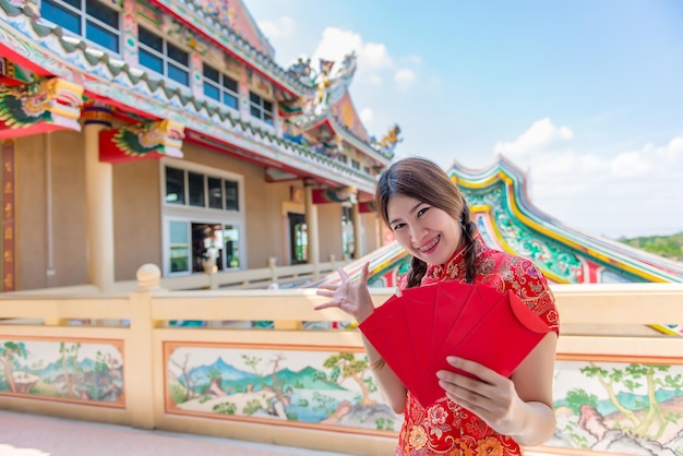 Portrait of beautiful asian woman in Cheongsam dress with Red envelope in handThailand peopleHappy Chinese new year concept