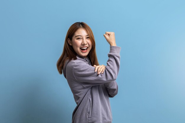 Portrait of beautiful Asian woman doing cheerful pose on isolated background portrait concept used for advertisement and signage isolated over blue background copy space