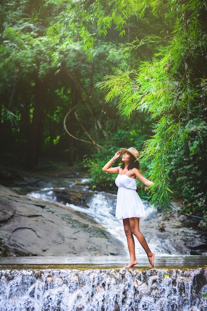 Portrait of beautiful Asian woman enjoy water fall, natural outdoor at forest