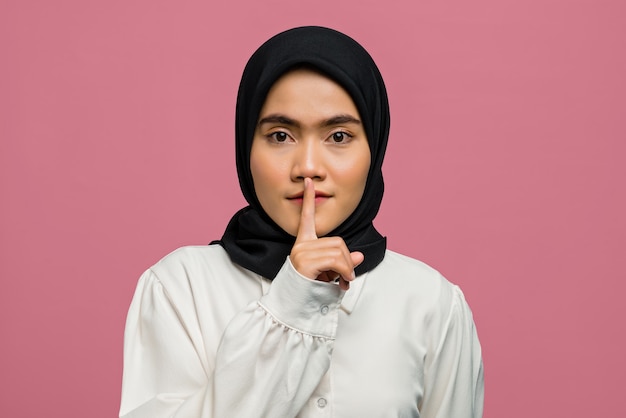 Portrait of beautiful Asian woman gesturing for silence and looking at camera