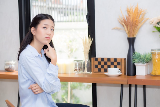 Portrait beautiful asian woman happiness and think sitting at cafe shop