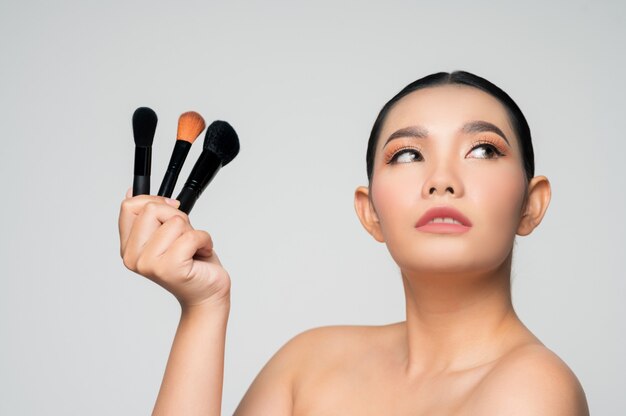 Portrait of Beautiful Asian woman holding makeup blusher brush