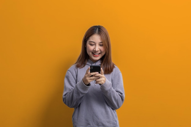 Portrait of beautiful Asian woman holding mobile phone on isolated background portrait concept used for advertisement and signage isolated over yellow background copy space