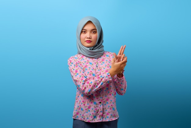 Portrait of beautiful Asian woman holding symbolic gun with hand gesture