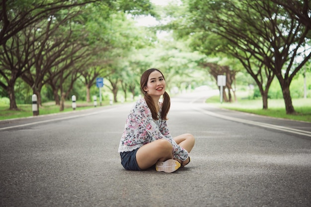 Portrait of beautiful asian woman sit on the road under tunnel treeshappy woman in the forest vintage styleretrothailand people