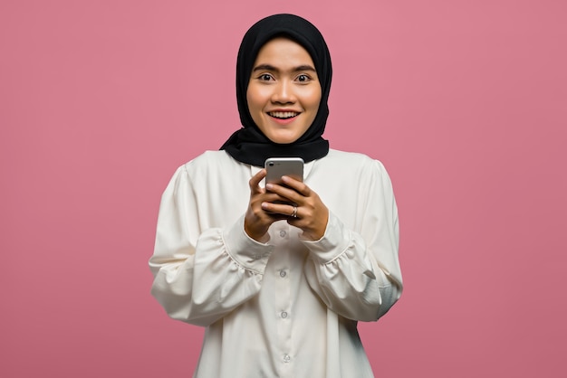 Портрет красивой азиатской женщины, улыбающейся и держащей смартфон