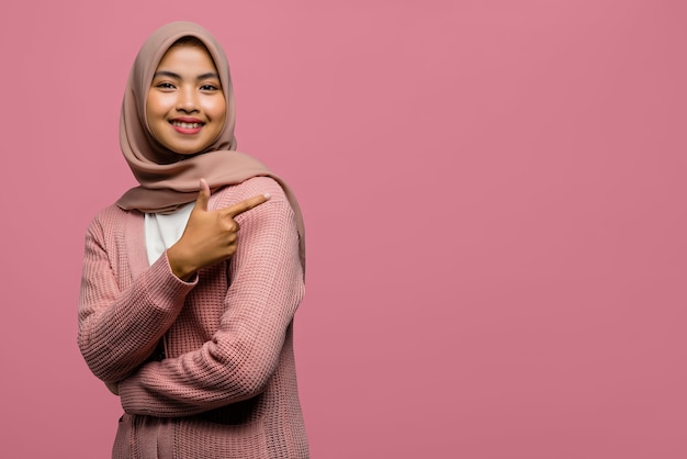 Portrait of beautiful Asian woman smiling and pointing with finger to empty space