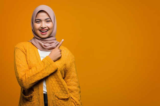 Portrait of beautiful Asian woman smiling and pointing with finger to empty space