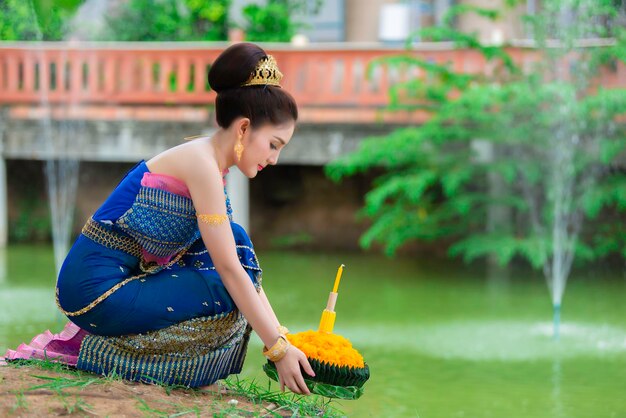 Portrait of beautiful asian woman in Thai dress traditional praying hold kratong for join loy kratong festival at thailand